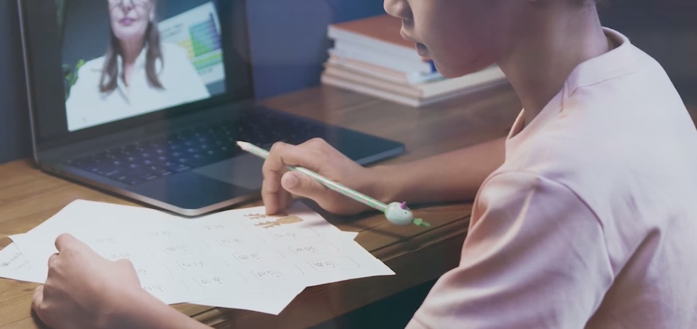 A student writing with reference notes beside them